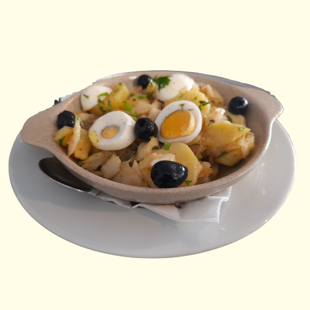 Nuestro Bacalhau à Gomes de Sá se prepara con bacalao de Noruega, desmigado con cuidado y combinado con patatas gallegas cocidas en su punto, cebolla tierna laminada, huevos camperos cocidos y aceitunas negras de Aragón. El toque final lo da un generoso chorro de aceite de oliva virgen extra de [menciona la variedad si quieres destacar]. ¡Una experiencia de sabor única!